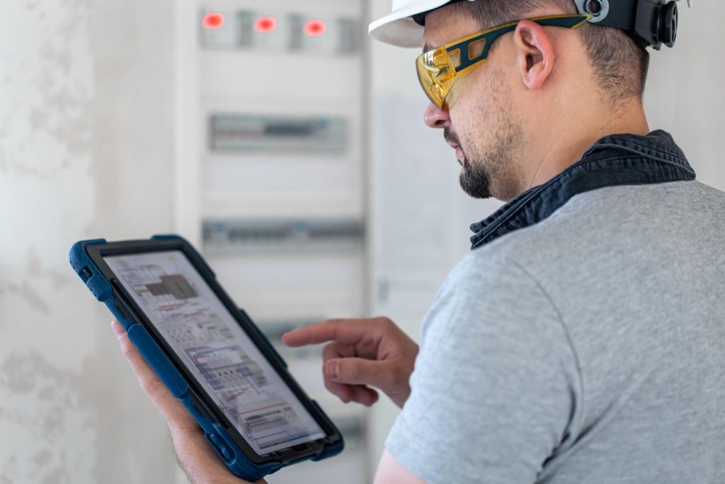 electrical technician looking focused while working switchboard with fuses